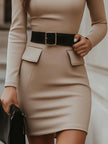 Beige turtleneck bodycon dress by FJØRNA with black belt accent, form-fitting design, and elegant silhouette.