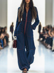 Dark blue FJØRNA denim jumpsuit with wide-leg pants, topstitch detailing, and long sleeves, styled for a casual look.