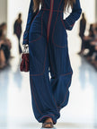 Dark blue FJØRNA denim jumpsuit with topstitching, wide-leg design, long sleeves, and a fitted waist on a model.
