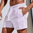 Men's casual striped boardshorts by FJØRNA with blush pink color, drawstring waist, and side slit hem for a relaxed summer look.