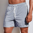 Men's gray striped FJØRNA casual boardshorts with drawstring waist and side slit hem, suitable for relaxed beach or pool days.