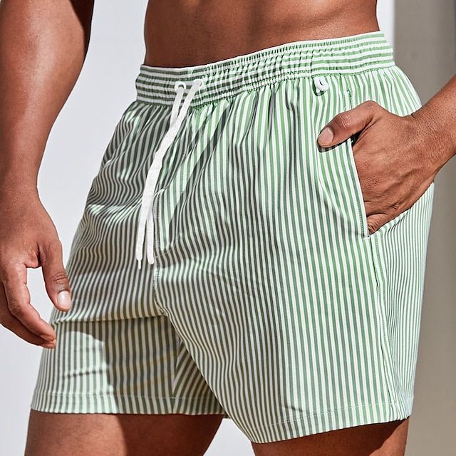 Men's casual striped boardshorts by FJØRNA featuring a drawstring waist and side slit hem in green.