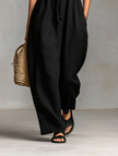 FJØRNA linen blend strapless women's jumpsuit with loose fit and tie closure, shown as stylish pants on a model.