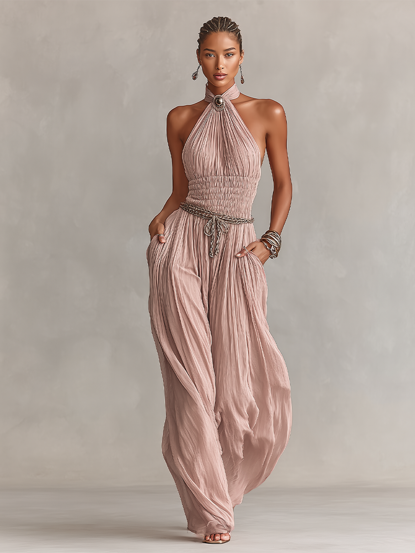 FJØRNA blush pleated women's jumpsuit with halter neck, ruched waist, and wide-leg pants, shown in the product image.