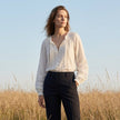 FJØRNA summer women's blouse featuring a V-neck, long sleeves, lace details, and ruffle accents in a casual lifestyle setting.