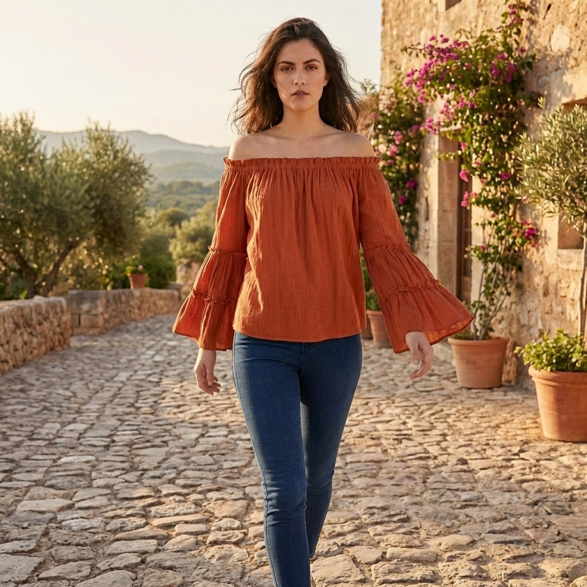 FJØRNA women's off-shoulder summer blouse with bell sleeves, stylish casual top for warm weather, worn in a lifestyle setting.