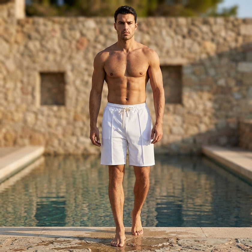 Men's relaxed knee-length tailored shorts by FJØRNA with adjustable waist and stylish seam details, worn in a casual outdoor setting.