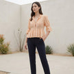 FJØRNA women's summer blouse with V-neck, puff sleeves, and lace details, styled in a casual outdoor setting.