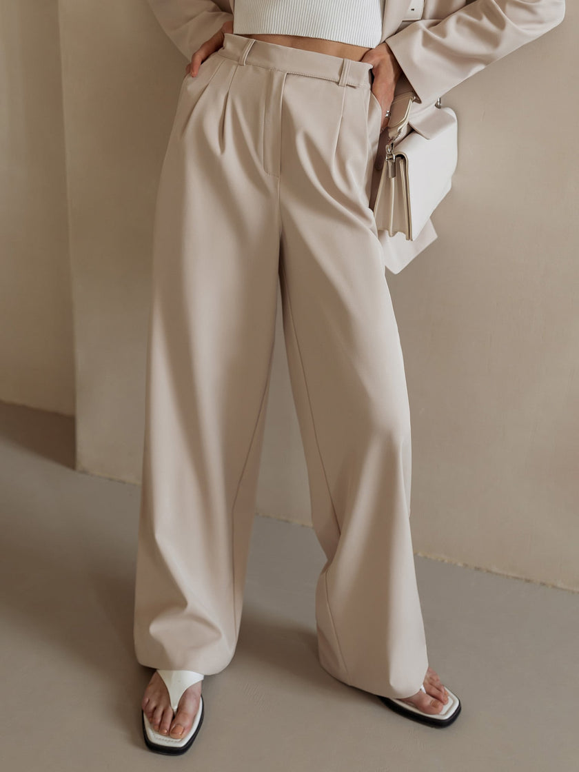 FJØRNA women's wide-leg high-waist trousers, stylish and comfortable pants, shown in a neutral color on a model.