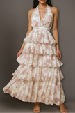 Off-white FJØRNA halter maxi dress with tiered ruffles, floral print, and waist detail, perfect for summer or special occasions.