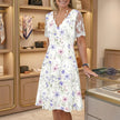 FJØRNA elegant floral midi dress for women with V-neck, flowing fabric, and stylish design ideal for spring and summer.