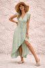 Sage green asymmetric dress by FJØRNA featuring flowing fabric and elegant drape, displayed on a dress form.