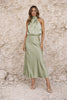 Sage green satin dress by FJØRNA featuring a flowing design and elegant fabric, shown on a model in a stylish setting.