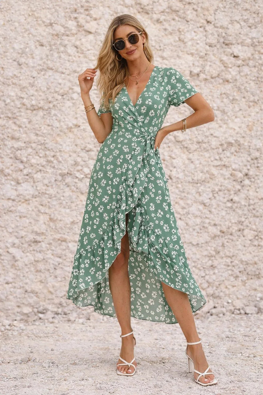 Sage green FJØRNA wrap dress with a slit, featuring a flattering neckline and flowing fabric, styled for elegant occasions.
