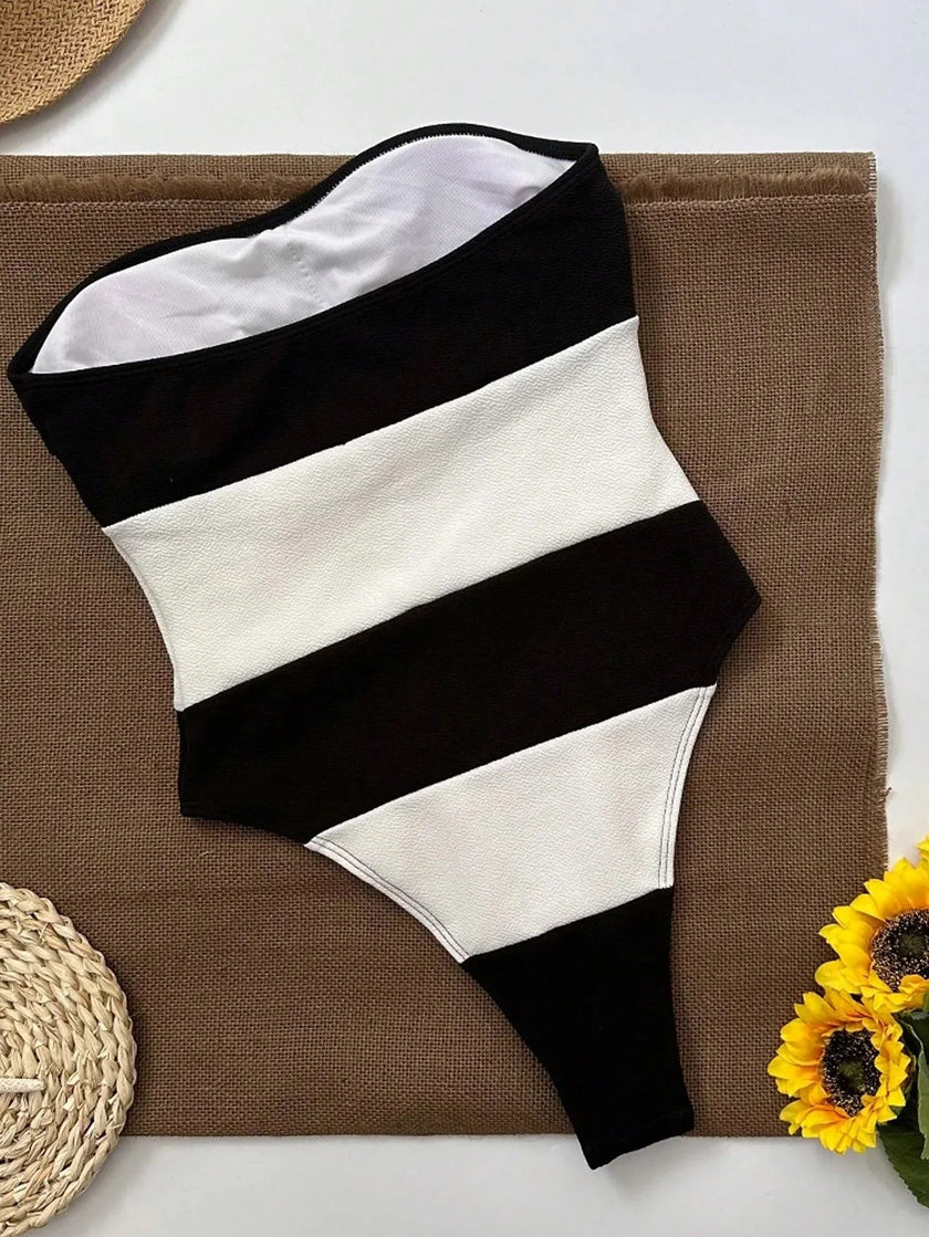 Women's off-shoulder striped jumpsuit with high leg cut by FJØRNA, featuring contrast stripes and a stylish, relaxed fit.