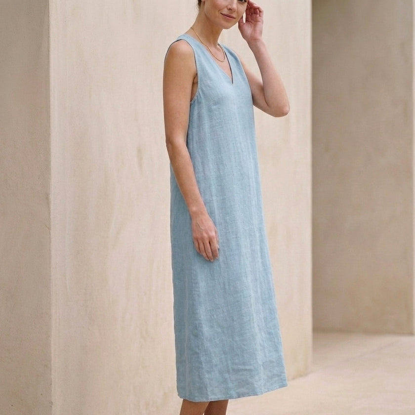 Side view of FJØRNA elegant sleeveless midi dress for women with a V-neck, showcasing a flowing fabric and stylish design.