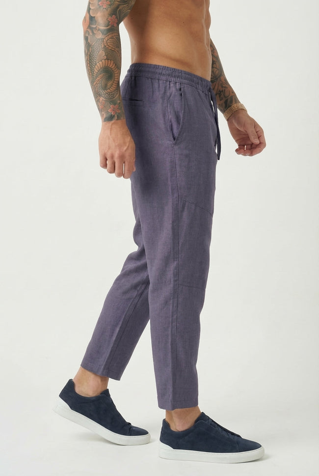 Men's cropped linen trousers in indigo by FJØRNA, showing relaxed fit with lightweight fabric and stylish design.