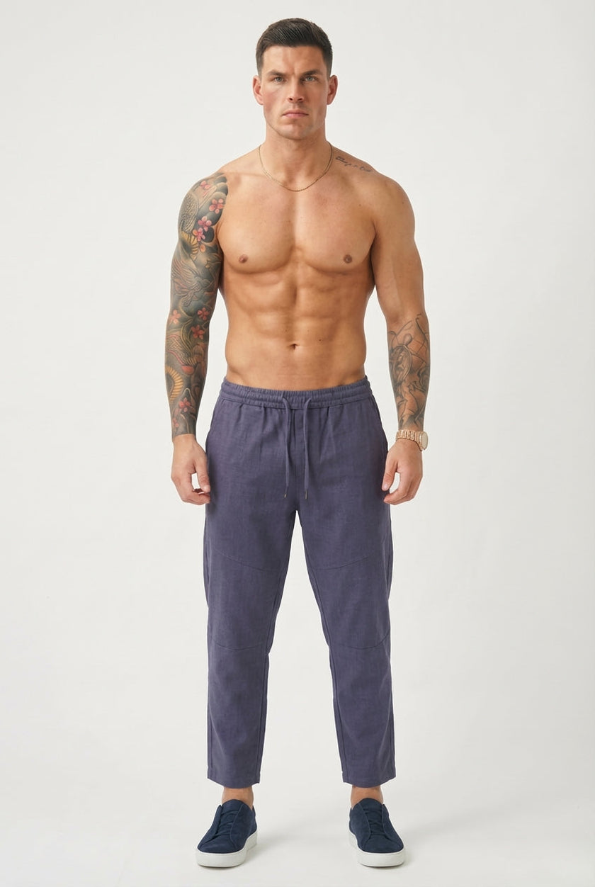 FJØRNA cropped linen trousers in indigo laid flat showing relaxed fit and lightweight fabric.