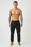 Black cargo jogger trousers by FJØRNA, featuring adjustable waist and multiple pockets, styled on a model.