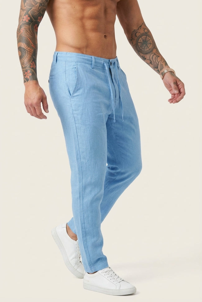 Men's beige relaxed linen trousers by FJØRNA, shown on a model with a casual fit and lightweight fabric.