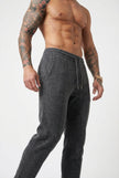 FJØRNA Merino Wool Trousers in dark grey, tailored fit with soft wool fabric, showcased on a model in a casual setting.