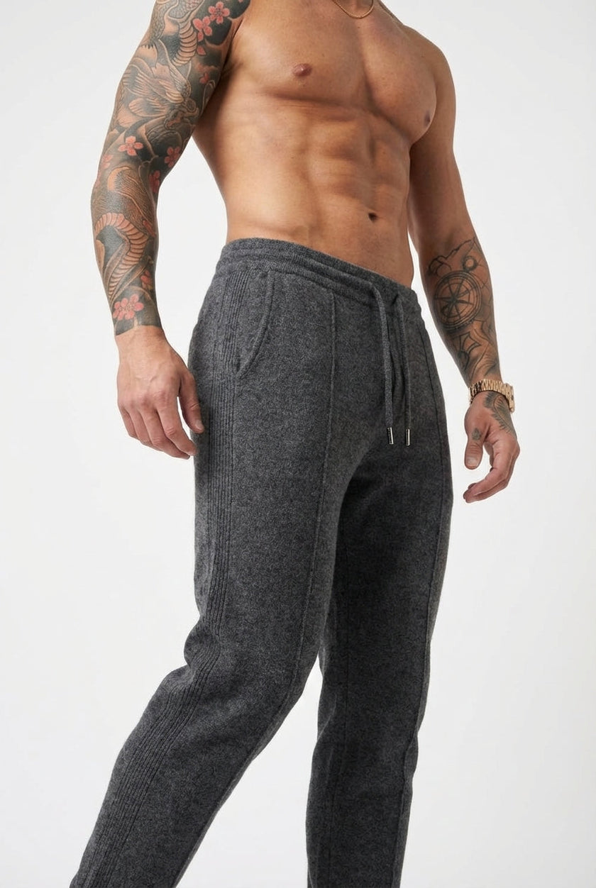 FJØRNA Merino Wool Trousers in dark grey, tailored fit with soft wool fabric, showcased on a model in a casual setting.