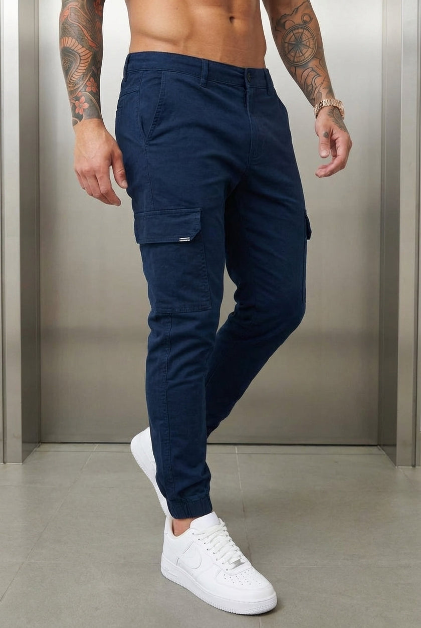 FJØRNA navy cargo jogger trousers displayed on a model, featuring multiple pockets and a relaxed fit for casual wear.