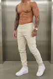 Cream cargo jogger trousers by FJØRNA, featuring a relaxed fit, multiple pockets, and casual style, displayed on a model.