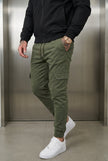 FJØRNA cargo jogger trousers in army green with multiple pockets and relaxed fit, displayed on a hanger.