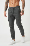FJØRNA grey cargo jogger trousers with multiple pockets and relaxed fit, displayed on a model in a casual setting.