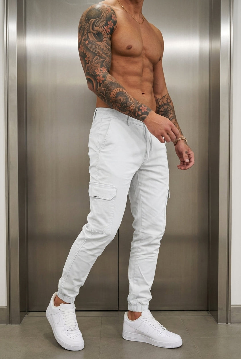 FJØRNA cargo jogger trousers in stone color, featuring relaxed fit, multiple pockets, and elastic waistband for casual comfort.