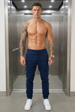 FJØRNA navy cargo jogger trousers displayed on a model, featuring relaxed fit, multiple pockets, and drawstring waist for casual style.