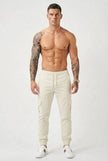 Cream cargo jogger trousers by FJØRNA, featuring a relaxed fit and multiple pockets, shown on a model.