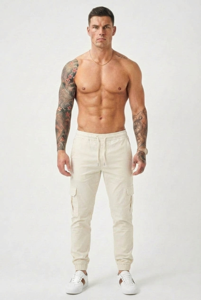 Cream cargo jogger trousers by FJØRNA, featuring a relaxed fit and multiple pockets, shown on a model.