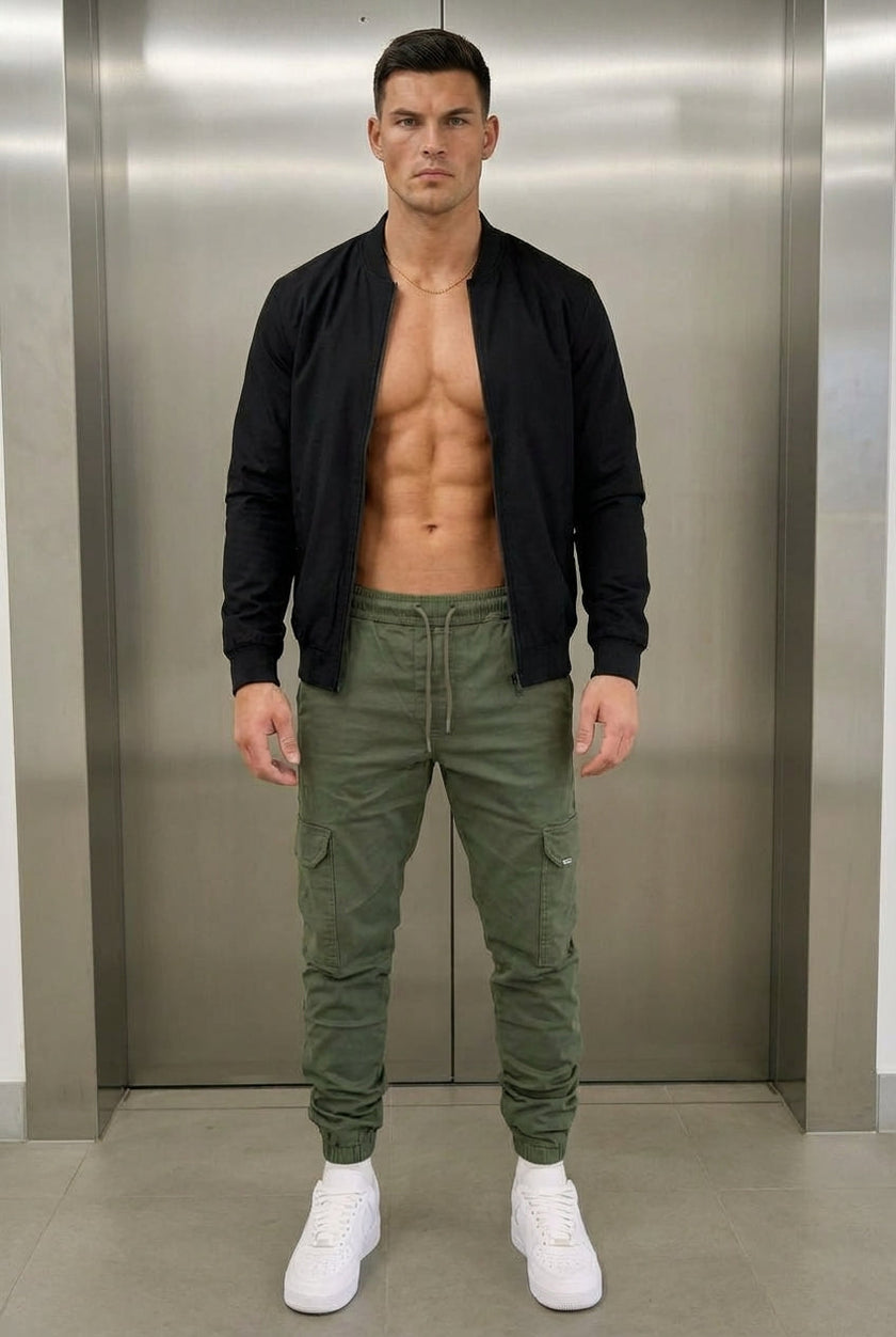 FJØRNA cargo jogger trousers in army green, featuring multiple pockets and a relaxed fit, displayed on a model.