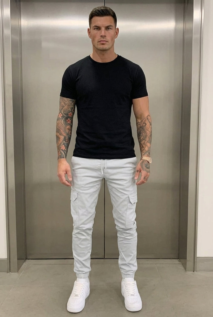 FJØRNA cargo jogger trousers in stone color, featuring relaxed fit and multiple pockets, displayed on a model.