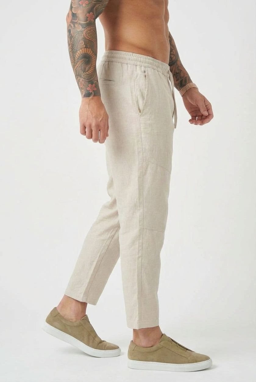 FJØRNA cropped linen trousers in indigo, showcasing a relaxed fit and lightweight fabric on a model.
