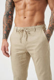 FJØRNA beige relaxed linen trousers displayed on a model, showcasing lightweight, casual fit and breathable fabric for comfortable wear.