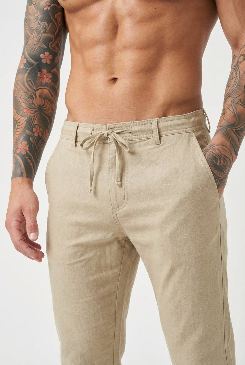 FJØRNA beige relaxed linen trousers displayed on a model, showcasing lightweight, casual fit and breathable fabric for comfortable wear.