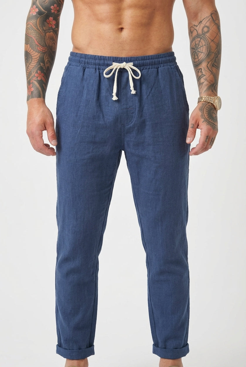 FJØRNA Linen tailored trousers in beige, featuring a slim fit and classic design, shown on a model in a casual setting.
