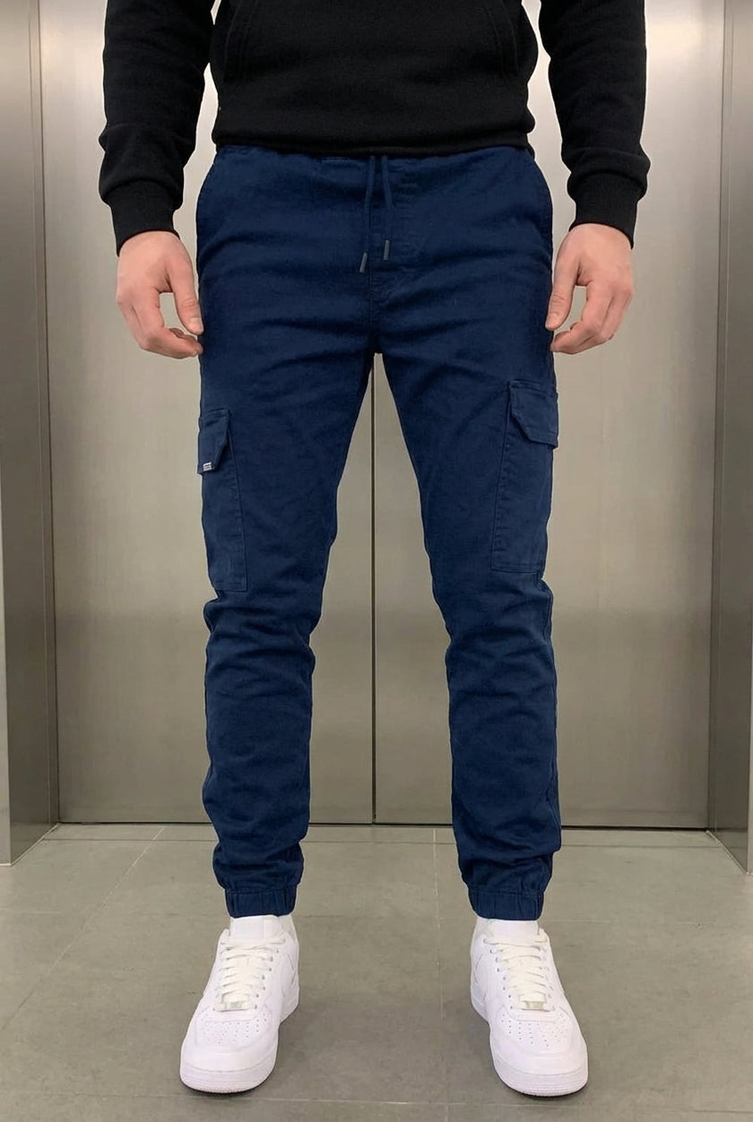 FJØRNA navy cargo jogger trousers displayed on a model, featuring multiple pockets and a relaxed fit for casual wear.