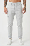 FJØRNA Cargo Jogger Trousers in stone color, featuring relaxed fit and multiple pockets, displayed on a model.