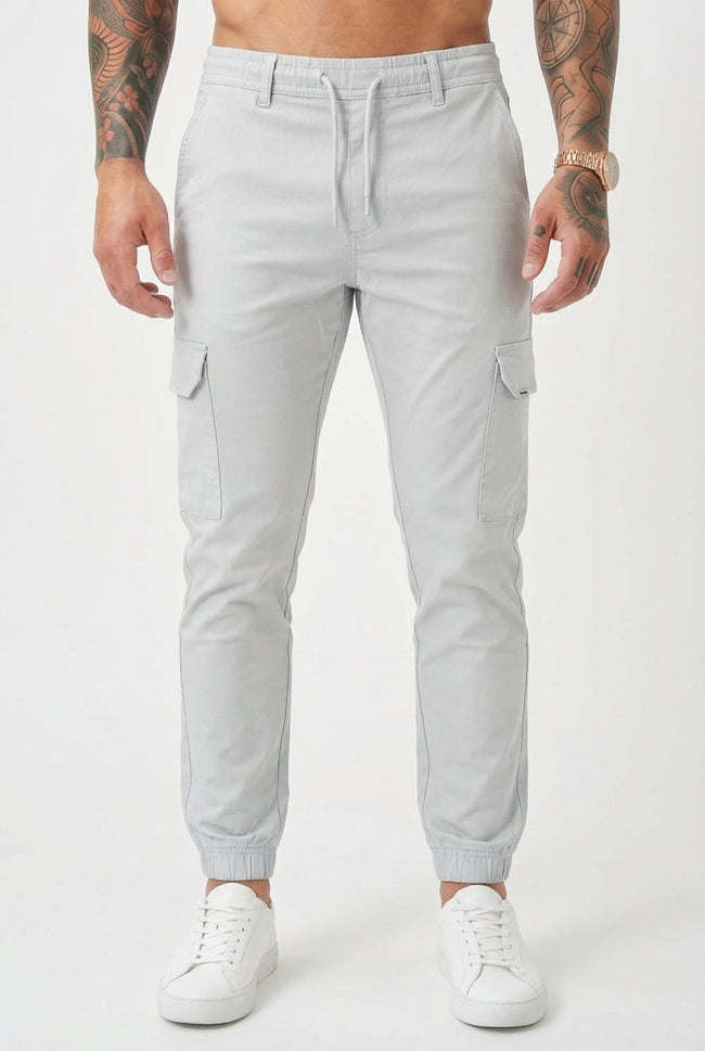 Men's cargo jogger trousers in stone color by FJØRNA, featuring relaxed fit and functional pockets, shown on a model.