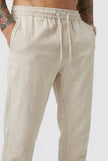 FJØRNA cropped linen trousers in indigo color, featuring a relaxed fit and lightweight fabric, styled with a casual top.