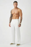 White tailored trousers by FJØRNA, featuring a sleek fit and classic design, shown on a model in a stylish indoor setting.