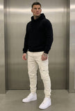 Cream cargo jogger trousers by FJØRNA, featuring a relaxed fit and multiple pockets, displayed on a model.