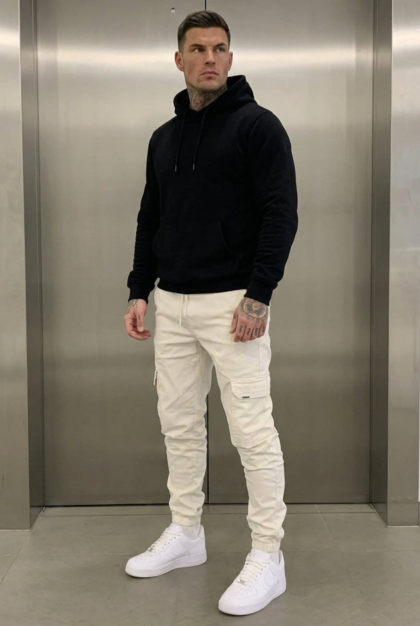 Cream cargo jogger trousers by FJØRNA, featuring a relaxed fit and multiple pockets, displayed on a model.