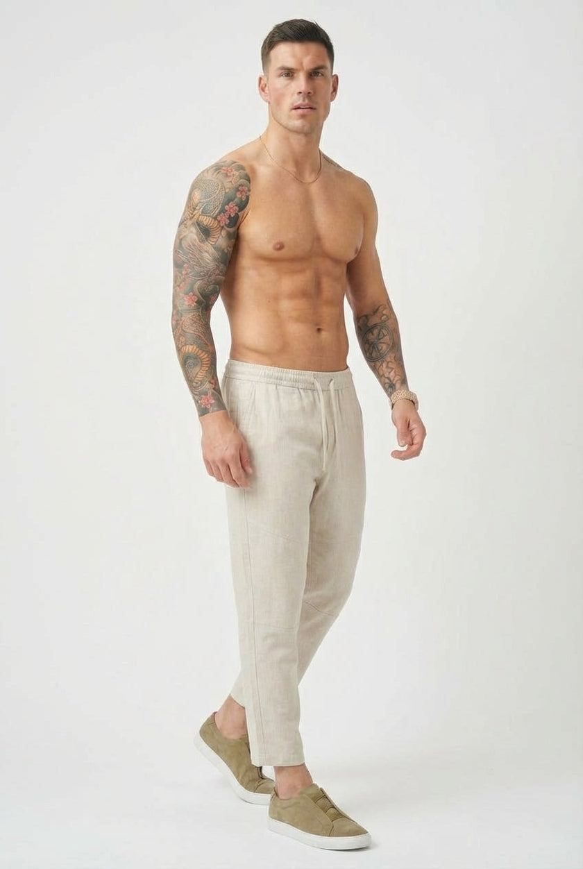 FJØRNA cropped linen trousers in indigo color, featuring a relaxed fit and lightweight fabric, styled with a casual top.