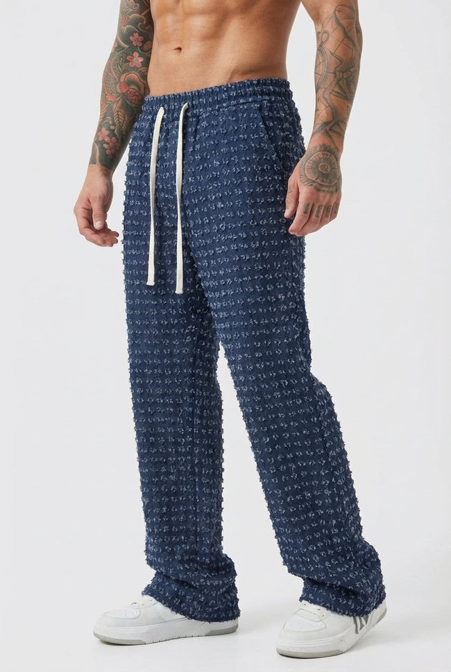 Black distressed men's trousers by FJØRNA, showcasing a casual fit with ripped details and rugged style.