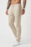 Beige relaxed linen trousers by FJØRNA, featuring a loose fit and lightweight fabric, displayed on a model.